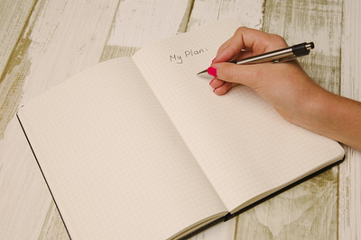Frau erstellt einen Plan in einem Buch mit Kugelschreiber
